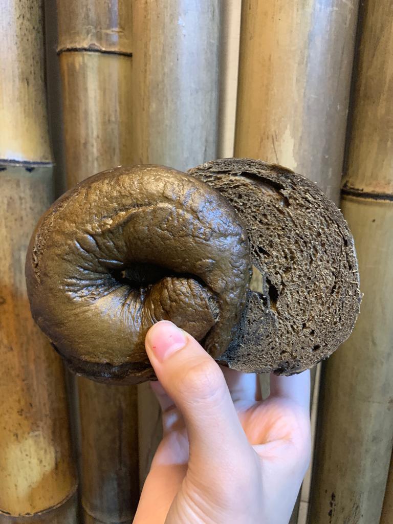 焙茶貝果切面細節，顯示炭焙色澤、高蛋白麵包體與純淨茶粉